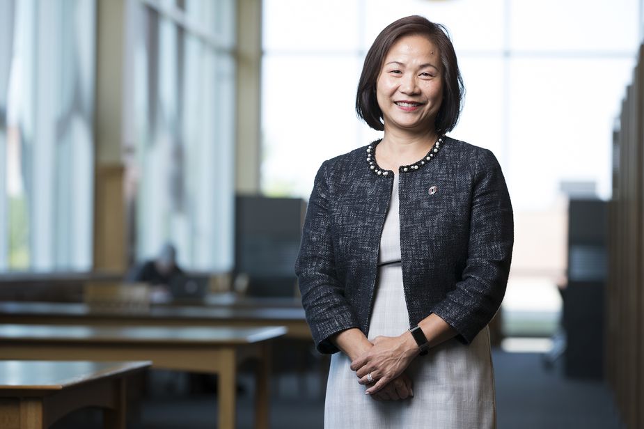 Joanne Li of the Kansas City Fed's Omaha Branch Board of Directors standing in front of windows.