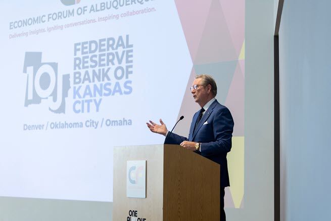 Jeff Schmid, president of the Kansas City Fed, speaks from behind a podium in front of a screen showing the Bank's logo.