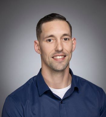 The photo is of a man in his 30s with short-cropped black hair, wearing a navy blue button-down shirt.