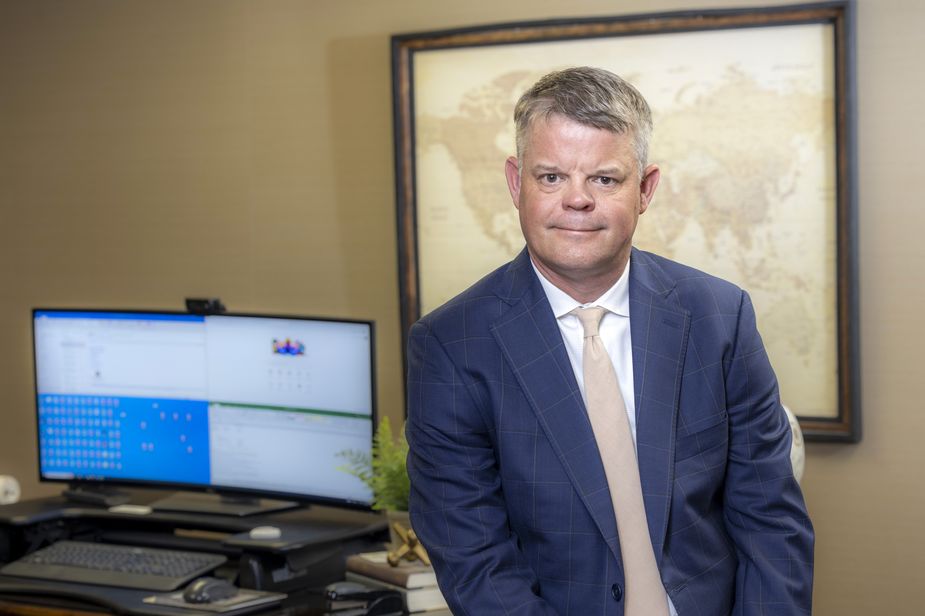 Mark Burrage of the Kansas City Fed's Oklahoma City Branch Board of Directors sitting on the edge of his desk.
