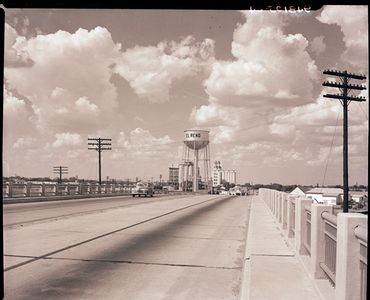 A sepia-toned photograph shows a car driving on Route 66 across a bridge just outside El Reno, Oklahoma.