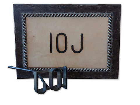 A metal branding iron in the shape of 10J in front of a framed photo showing an example of the brand.