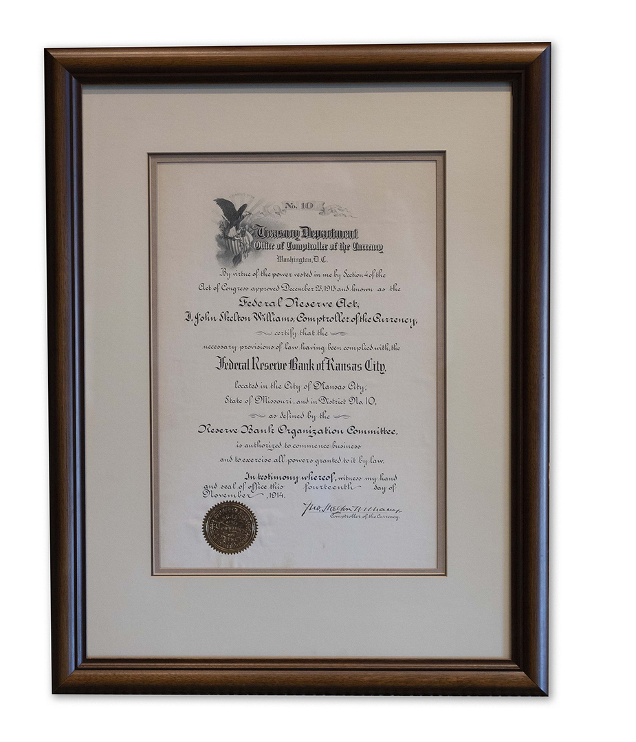 The KC Fed's national bank charter from 1914 in a wooden frame.