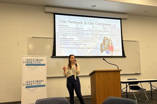 A young woman stands by a podium and talks about her nonprofit organization.