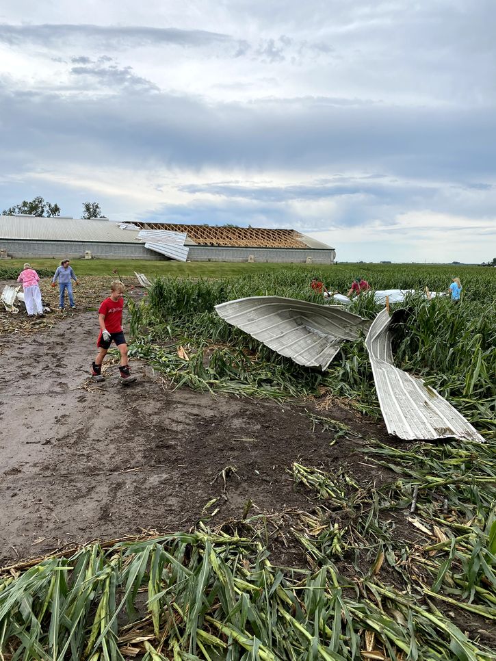 Family members retrieve parts of a large barn roof that was blown off during a derecho that hit Neal Keppy's farm.