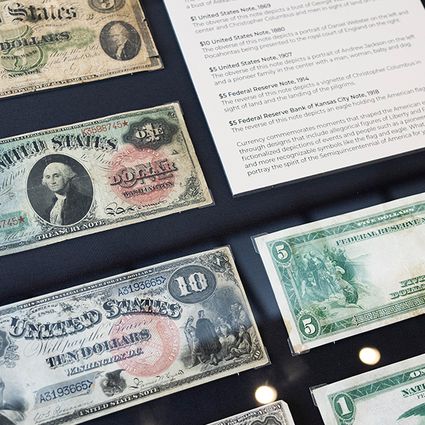 A display case showing various historic U.S. banknotes, each with unique designs and denominations, along with informational placards describing the currency.
