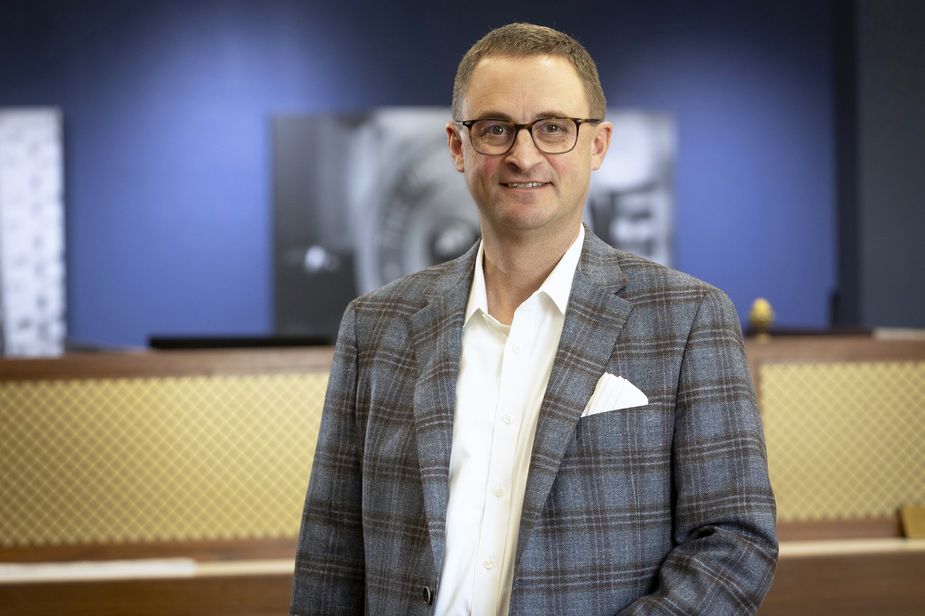 Alex Williams of the Kansas City Fed's Branch Board of Directors standing in front of a piece of art.