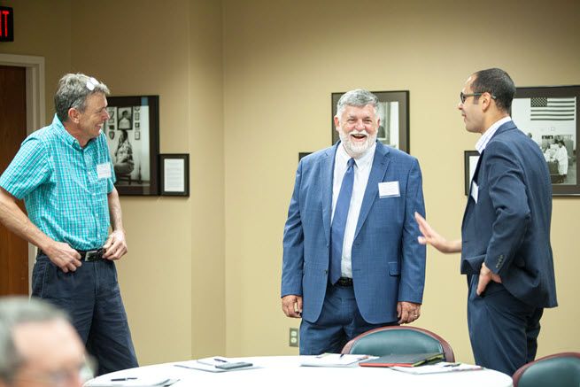 Three white guys joke around at a meeting.