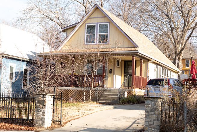 The photo shows a sweet little bungalow, a story and a half tall with a wide front porch, painted a soft yellow.