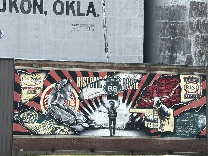 A mural commemorating Route 66 shows a man with a guitar facing forward into a sunrise.