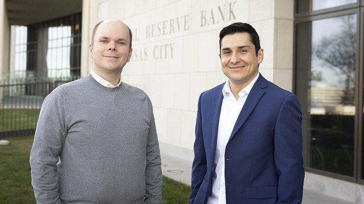 Kansas City Fed's Senior Economist Andrew Glover and Research and Policy Officer José Mustre-del-Río stand side by side in front of the Kansas City Fed building.