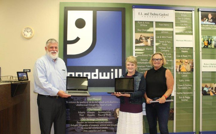Kansas City Fed Senior Community Development Advisor Steve Shepelwich stands next to employees from Oklahoma City's Goodwill organization holding laptop computers.