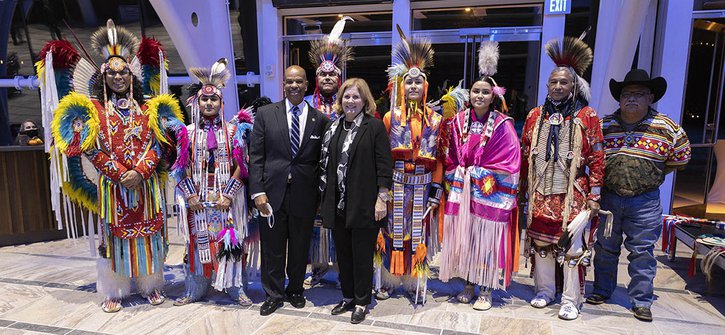 Kansas City Fed President Esther George standing next to Kansas City Board chair Edmond Johnson and members of the Native American troupe known as the Oklahoma Fancy Dancers.
