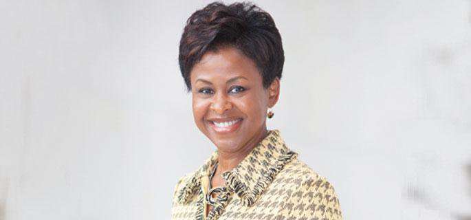 Image Description. Photograph of a woman of color with short, dark hair, smiling against a white background.